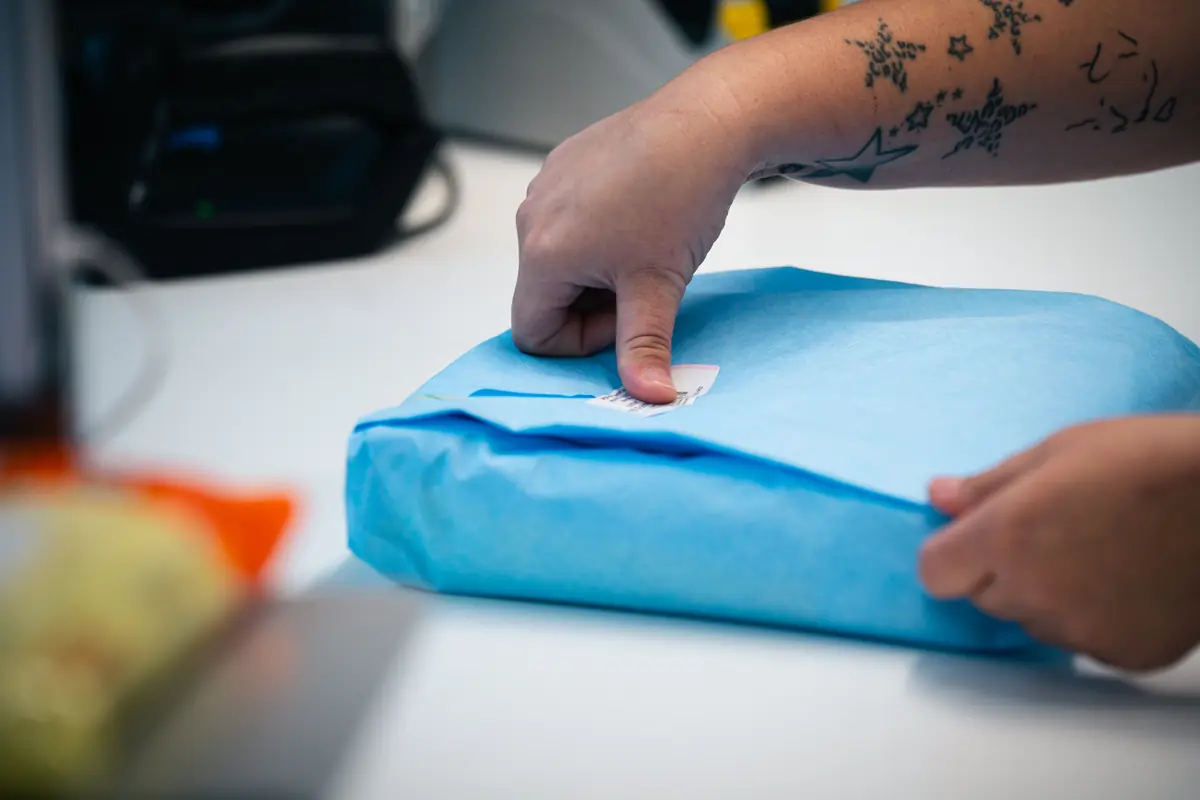 Gesiegeltes Sterilgutpaket in Vlies wird mit Barcode-Etikett gekennzeichnet